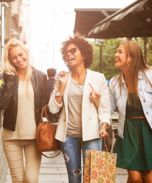 Three women walking outdoors with shopping bags