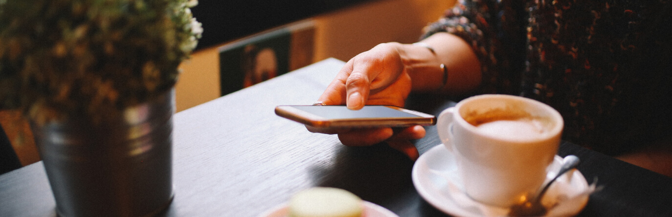 person using phone at coffee shop