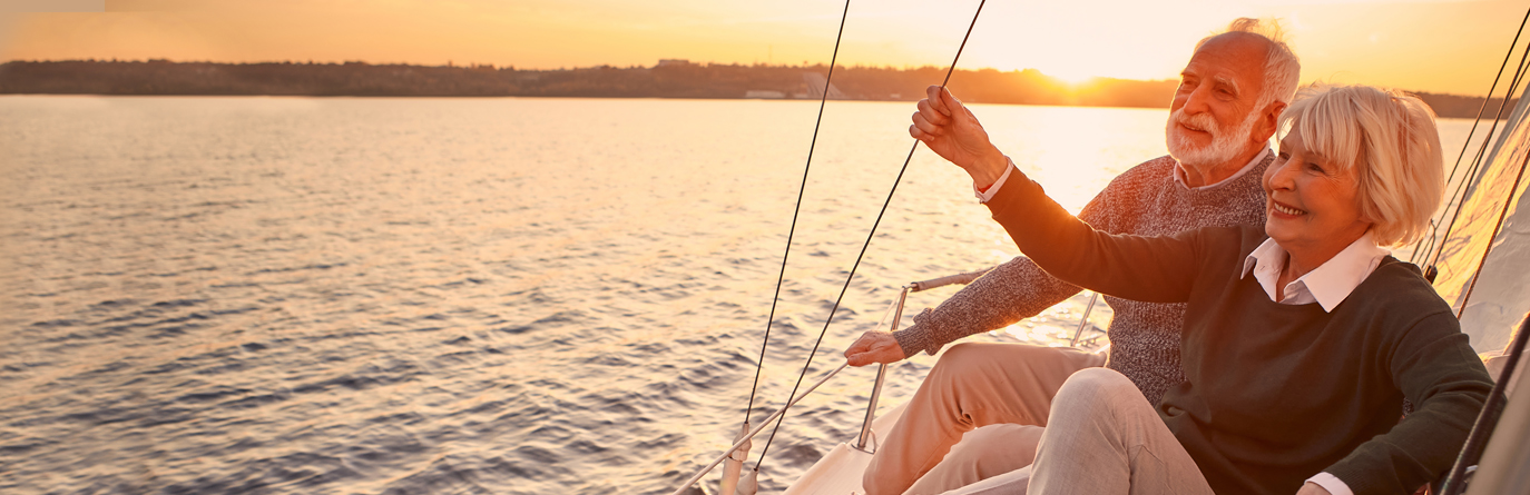 Elderly couple sailing on a boat during a sunset.
